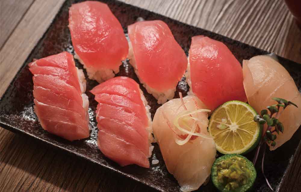 つややかな赤身マグロの握りと、白身魚、すだちが乗った7貫の寿司